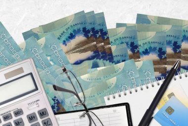 Tax return 2023 Canadian dollars bills and calculator with glasses and pen.