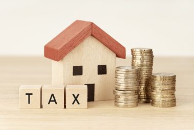 Concept of paying underused housing tax for housing and property. Debt payment. House model, money and wooden blocks with text
