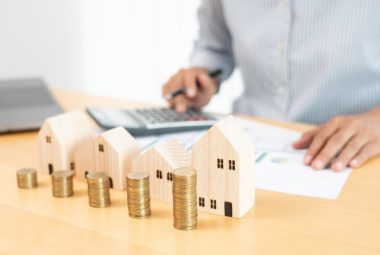 Underused Housing Tax Return and Election Form Property investment and house mortgage financial concept, hand of a businessman who is stacking coins for Real estate investment, saving for buying for housing or speculation