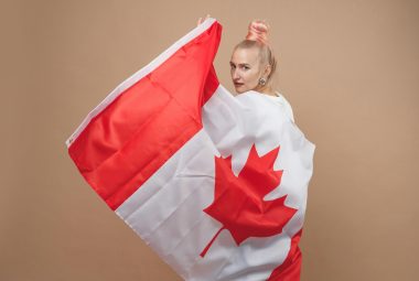 Beautiful blonde woman standing with Canadian flag Statutory Declaration of Single Status in Canada
