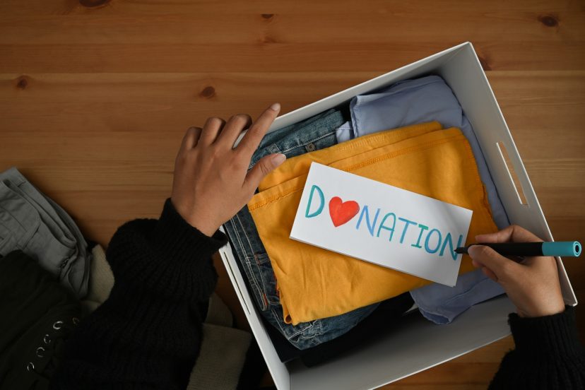 Woman packing clothes into donation box. Charity, donation and reuse recycle concept.